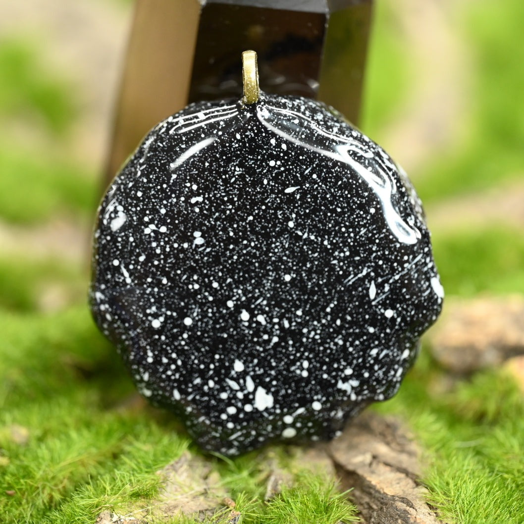 Back side of the GRiZ pinecone pendant, showing the painted starry black sky.